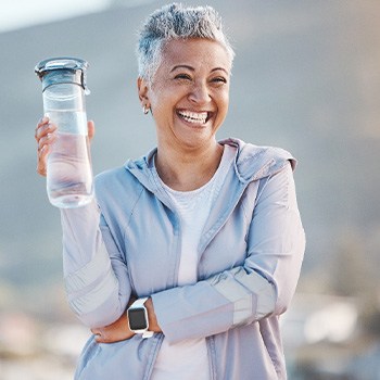 Woman smiling with water bottle on hike outside