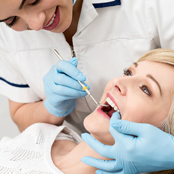Female patient having teeth cleaned by dentist