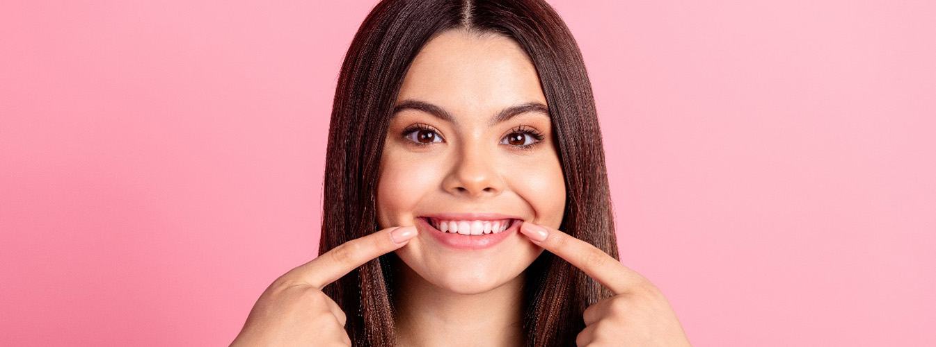 Woman pointing to her smile