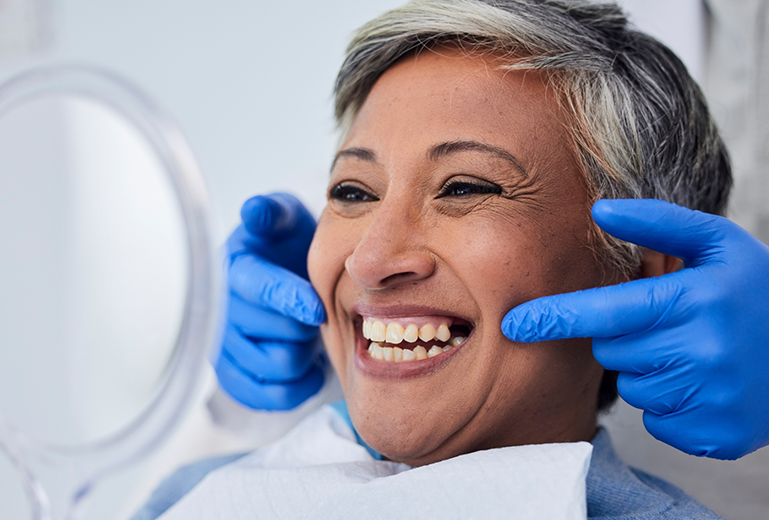 Senior woman in dental chair checking smile in mirror