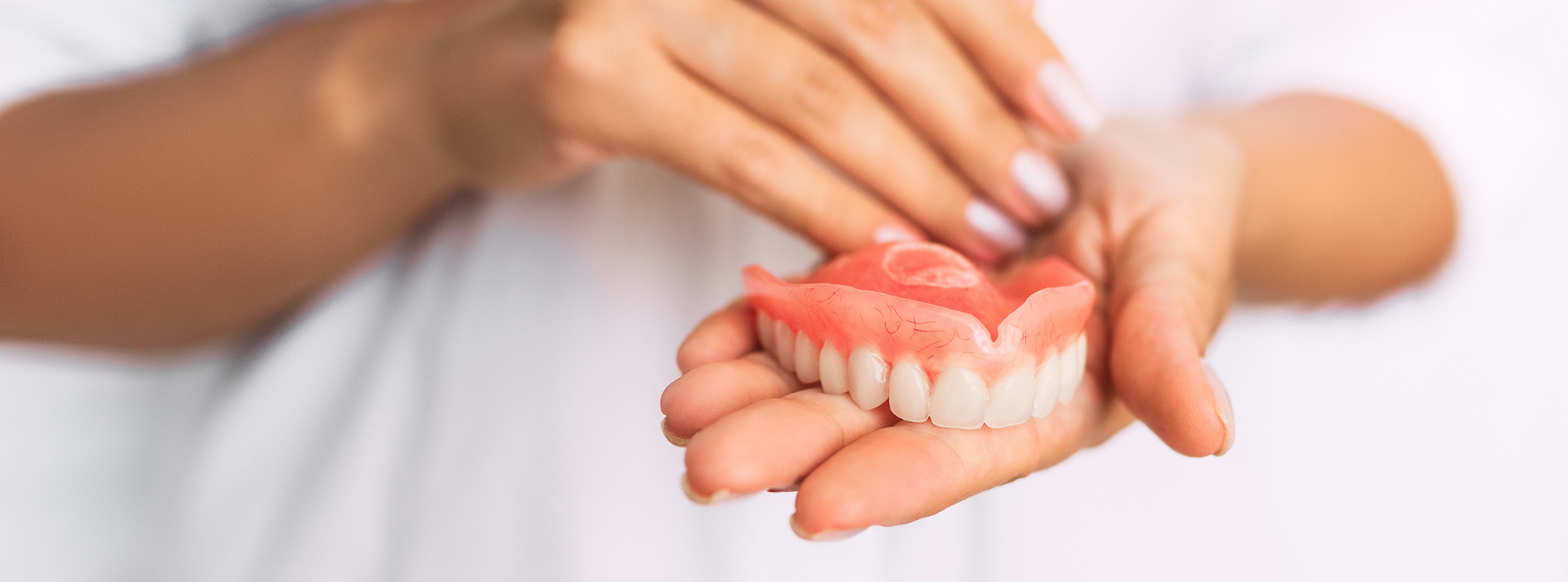 Close up of hands holding a full denture in Coppell