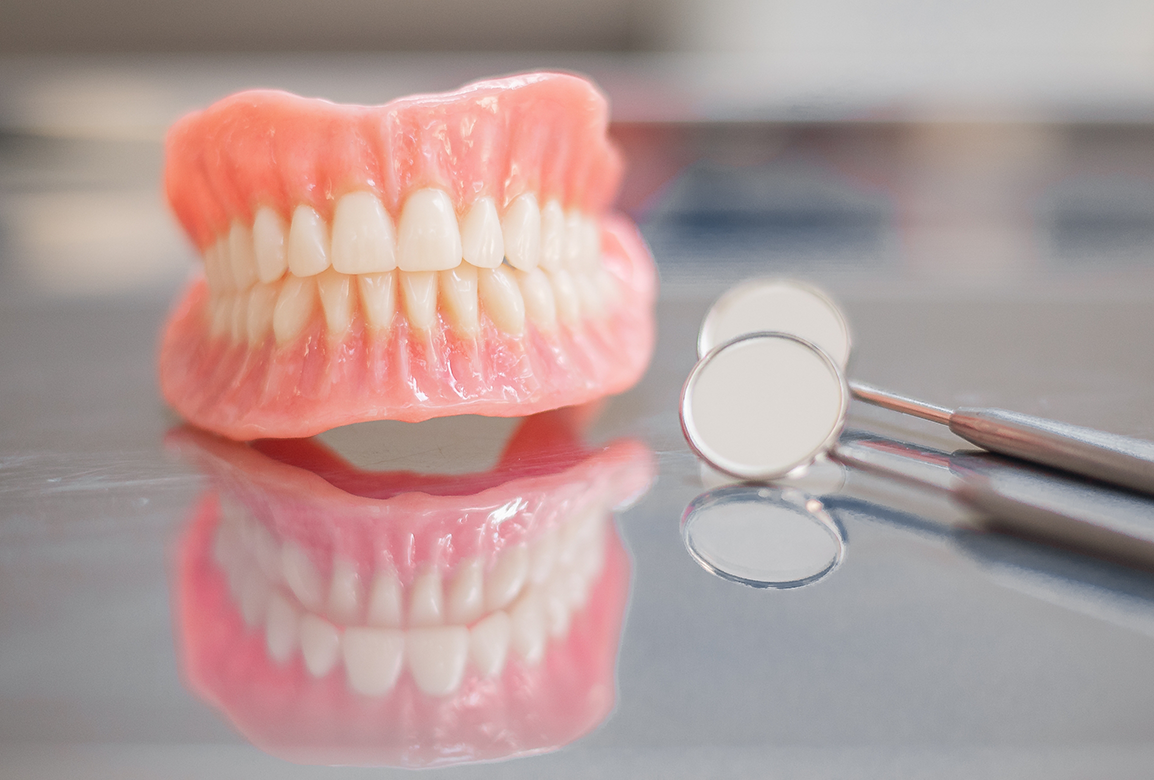 Full dentures and dental mirror on reflective surface