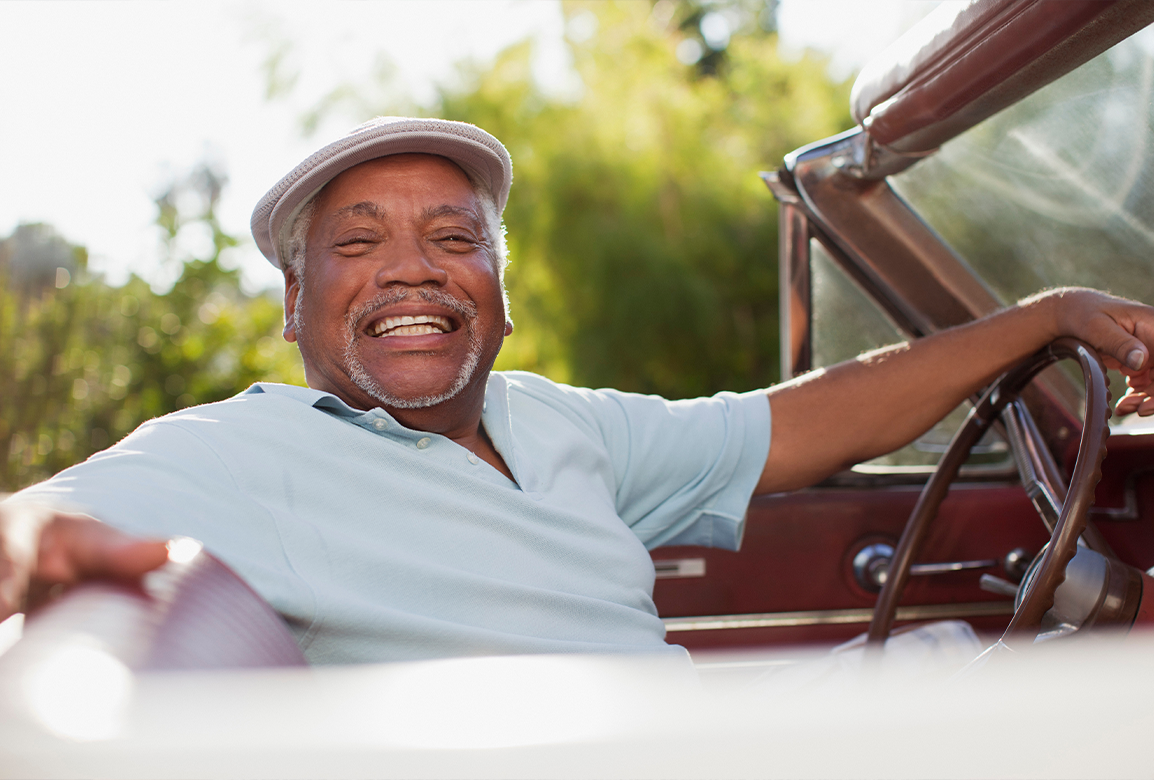 Senior man sitting in car and smiling