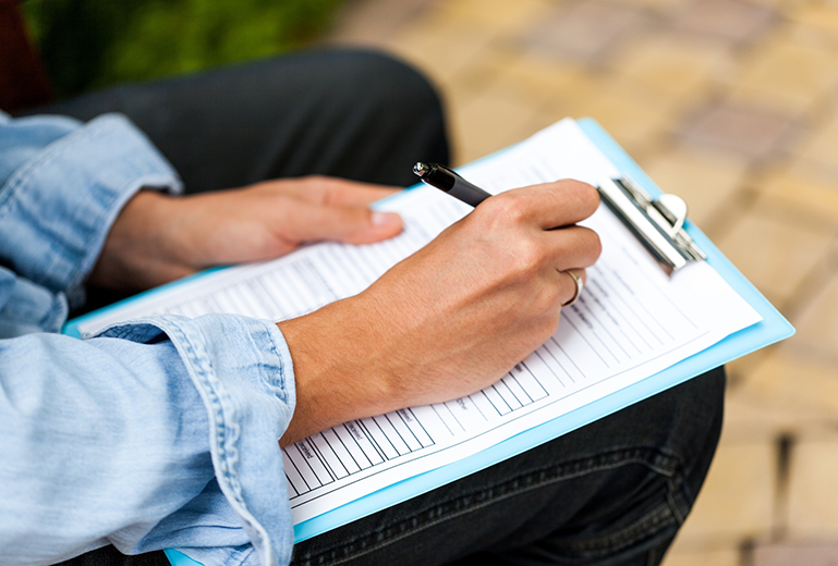 Close up of woman writing on clipboard