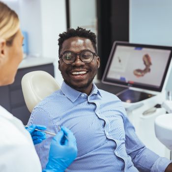 Male dental patient smiling and talking to dentist