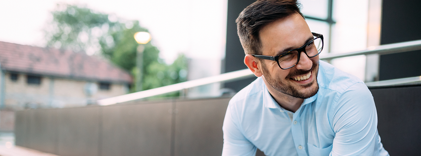 Man with glasses sitting and smiling