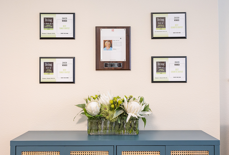 Awards on wall and flowers on small table