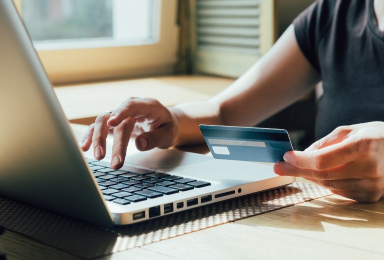 Holding credit card and typing on laptop