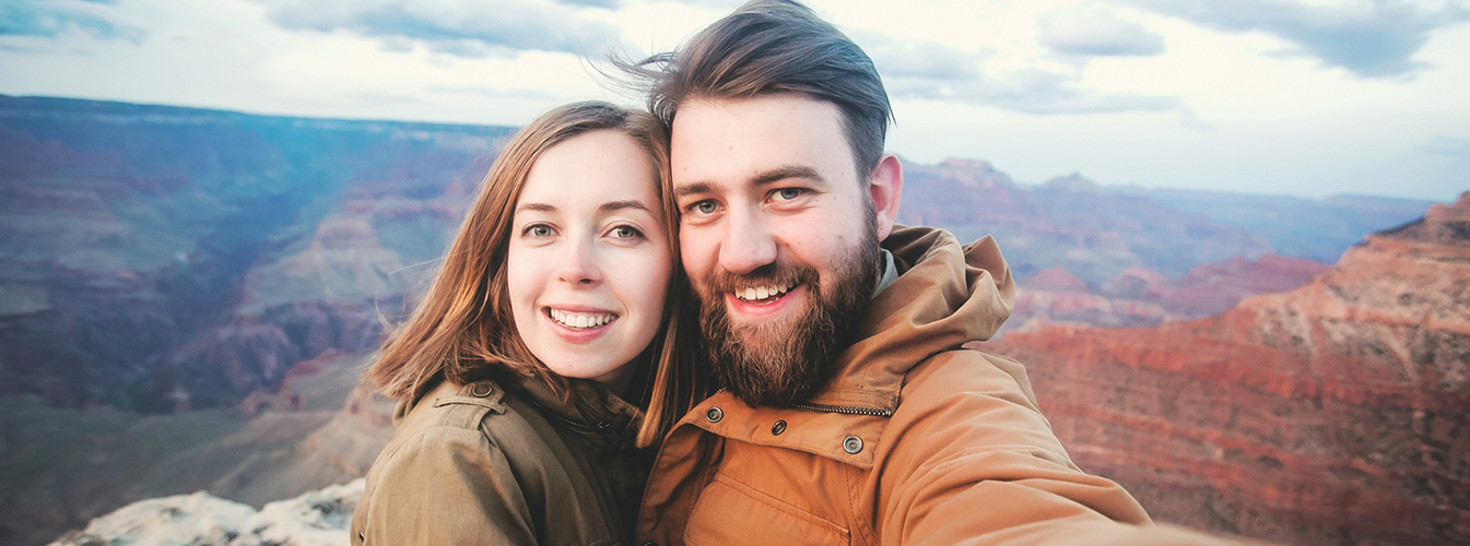 Man and woman standing in front of scenic view and smiling