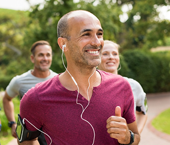 Smiling man jogging outside with others