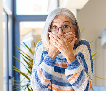 Woman in striped sweater covering her mouth