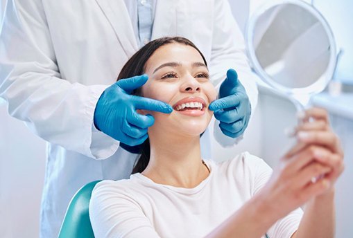 a patient checking her teeth with a mirror