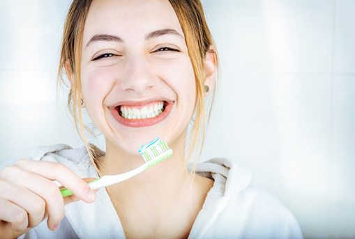 a woman smiling with bright smile while brushing her teeth
