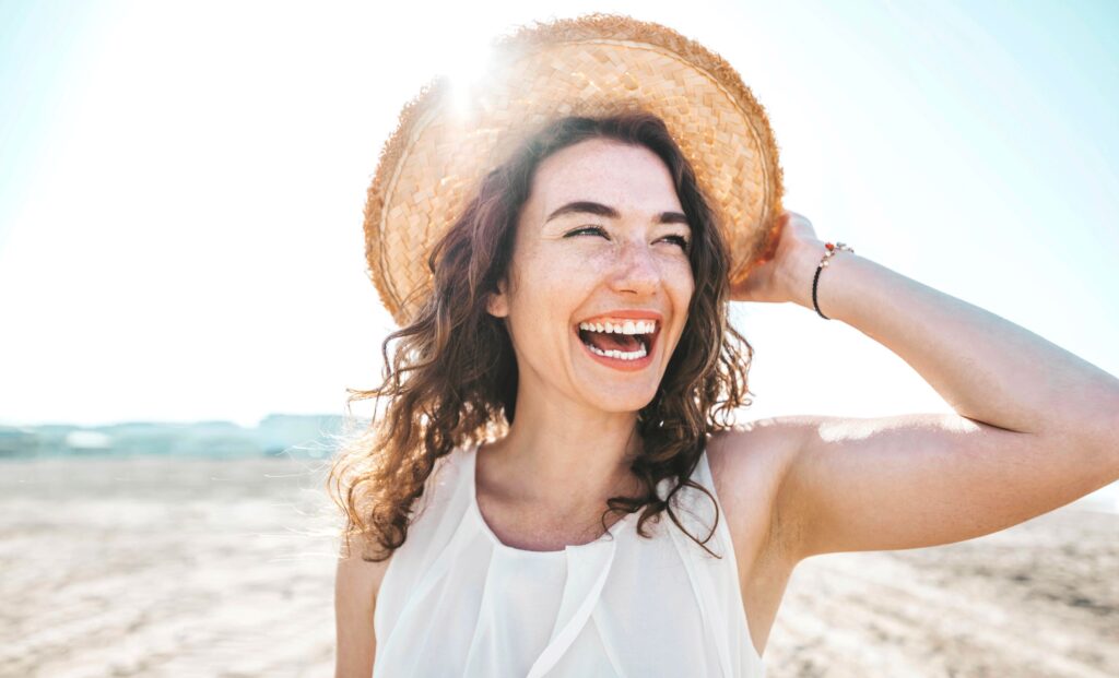 Woman in sun hat smiling at the beach
