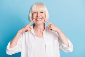 Woman pointing at her bright smile on blue background